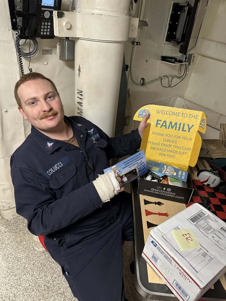 Sailor opening his Savior Sailor care package and reading the welcome message inside