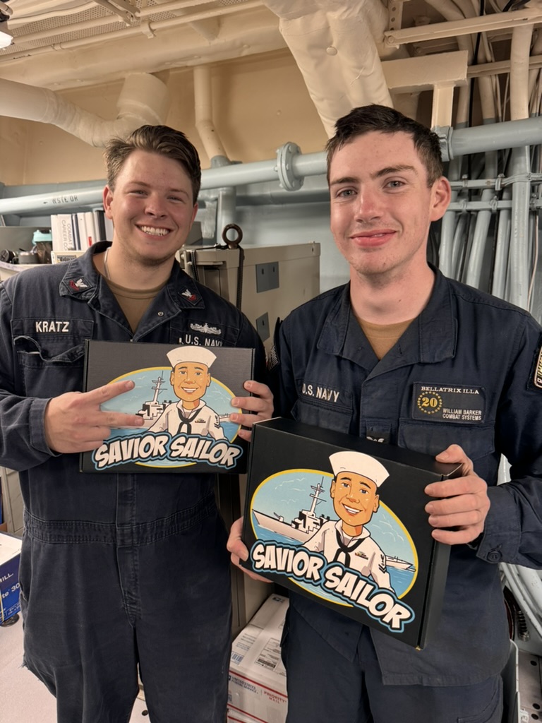 Two shipmates standing side by side, each holding their Savior Sailor care packages
